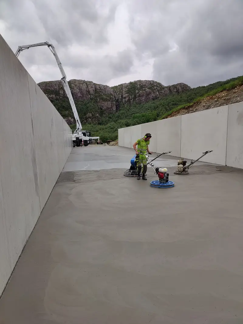 Fagarbeider glatter gulvet i plansiloen med glattemaskin mellom de 3 meter høye betongveggene