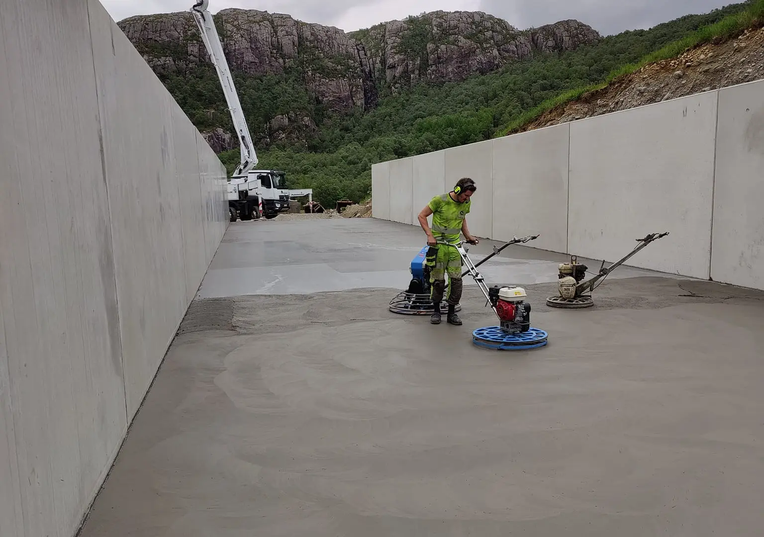 Fagarbeider glatter gulvet i plansiloen med glattemaskin mellom de 3 meter høye betongveggene