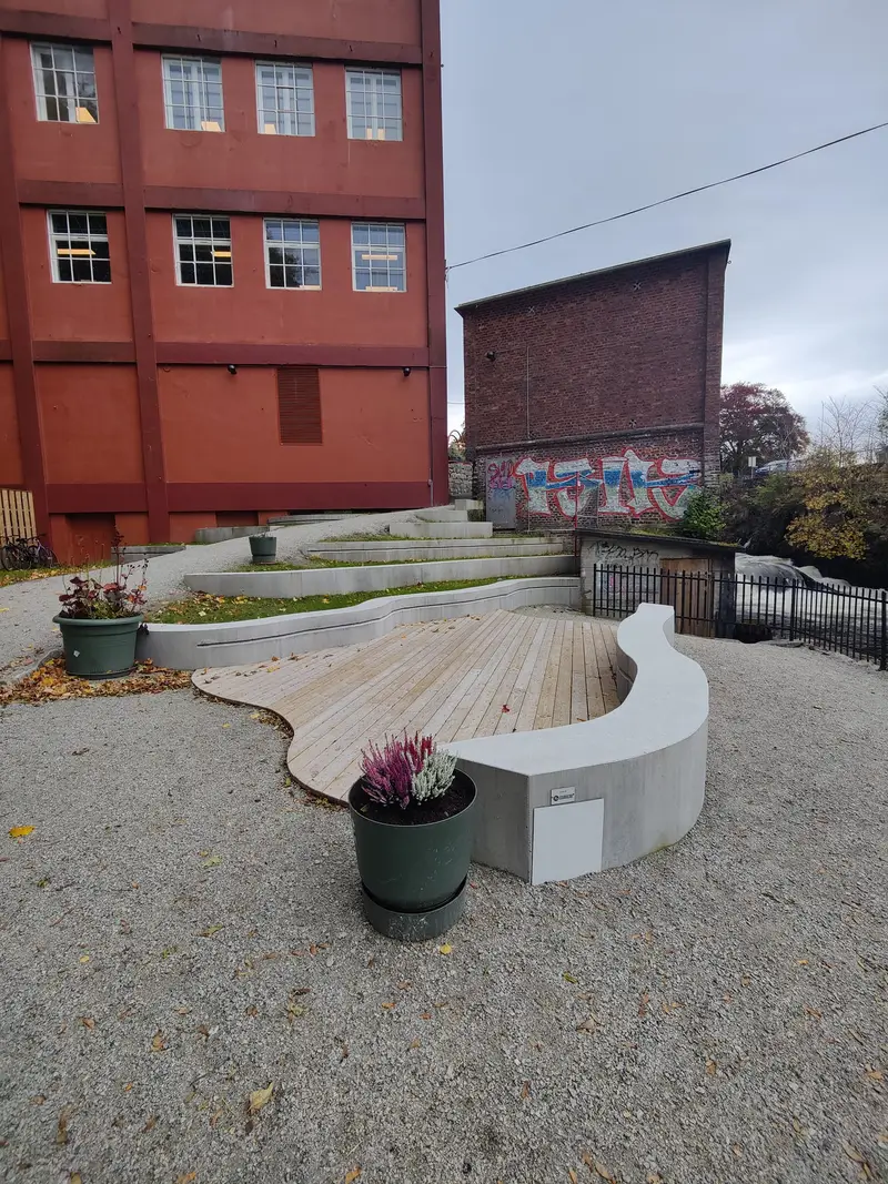 Treterrasse omkranset av en buet betongbenk