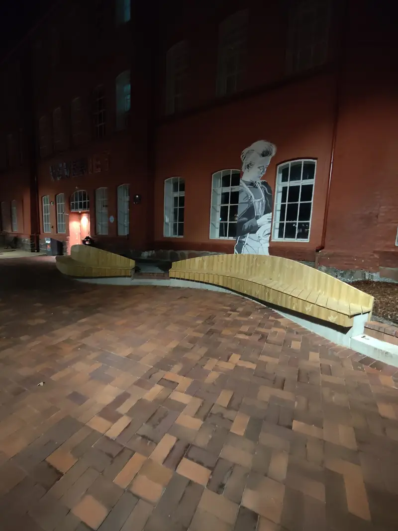 Sittebenker i betong og tre langs fasaden med veggmaleri